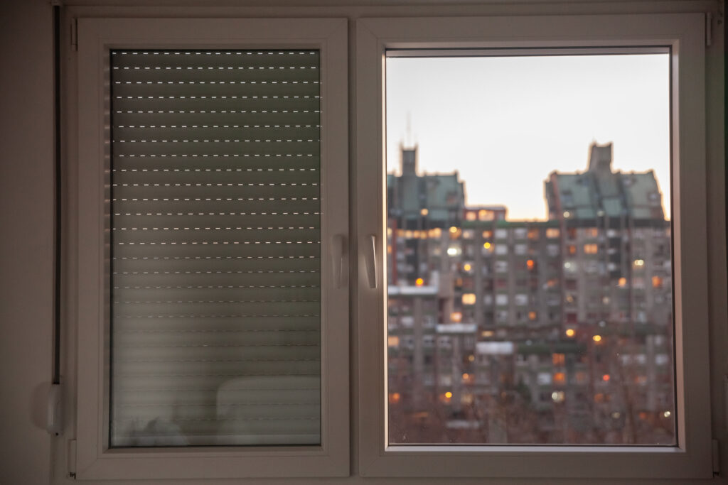 Fenêtre en PVC blanc qui donne sur la ville avec un volet manuel 